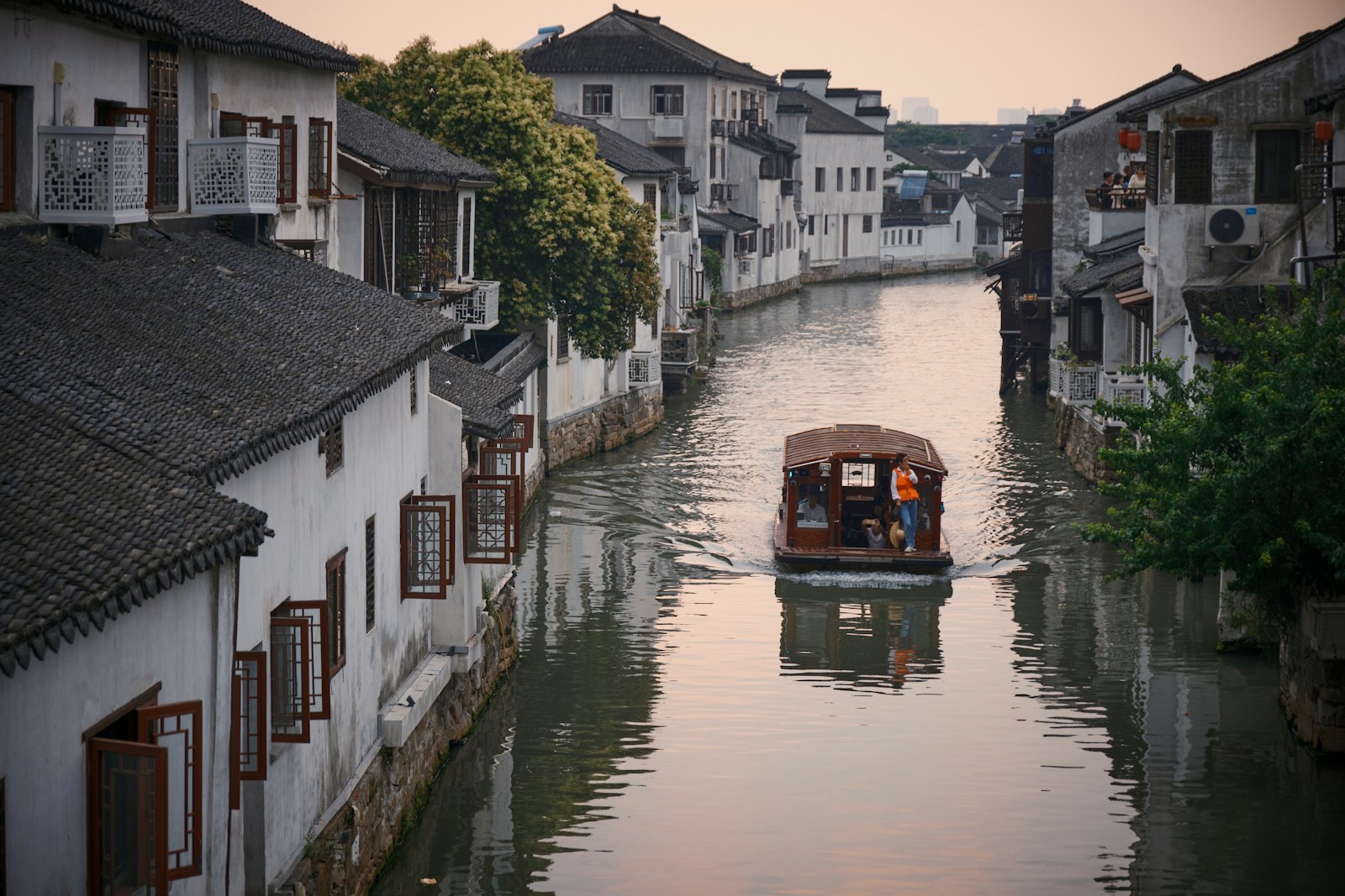 Barca recorriendo un canal entre casas tradicionales en Suzhou
